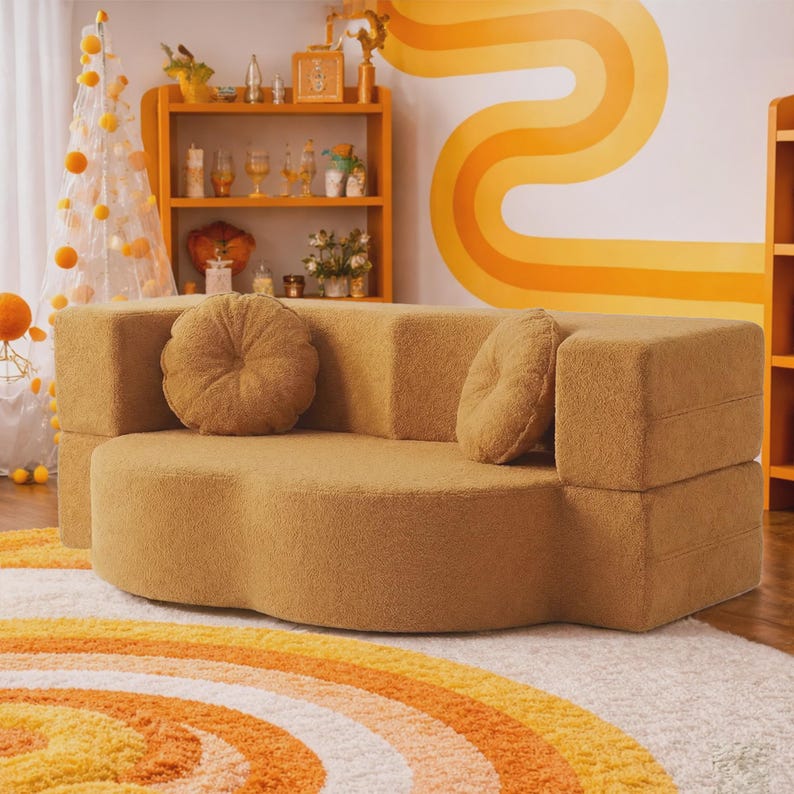 May include: A mustard yellow sofa with a textured, fuzzy fabric finish. The sofa features a curved, cloud-like seat design and two matching round, tufted throw pillows. The backrest is straight and rectangular, providing a contrast to the seat.