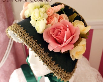 Op de afbeelding: Een groene fluwelen bonnet met gouden versiering en een tros roze en witte bloemen van stof.