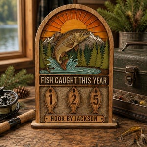 May include: A wooden arched display sign featuring a layered outdoor scene with a jumping trout, mountains, and pine trees. The text reads FISH CAUGHT THIS YEAR above three fish-shaped plaques displaying the number 125 and HOOK BY JACKSON.