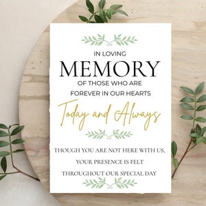 Puede incluir: Un letrero rectangular blanco con texto en negro y dorado que dice: IN LOVING MEMORY OF THOSE WHO ARE FOREVER IN OUR HEARTS Today and Always THOUGH YOU ARE NOT HERE WITH US, YOUR PRESENCE IS FELT THROUGHOUT OUR SPECIAL DAY, con detalles de hojas verdes.