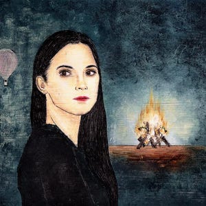 Puede incluir: Una mujer con el pelo largo y oscuro mira directamente al espectador. Lleva una camisa negra. Un pequeño globo aerostático está en el fondo a la izquierda. Un pequeño fuego está en el fondo a la derecha.