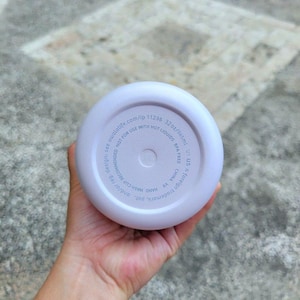 Puede incluir: La base circular de una botella de agua color lavanda claro con texto impreso que incluye 32oz/945ml, libre de BPA y no apto para l&iacute;quidos calientes. El texto tambi&eacute;n indica owalalife.com/ip 11296, se recomienda lavar a mano y fabricado en China.