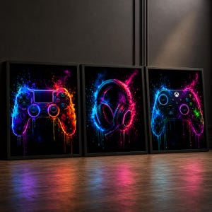 Könnte beinhalten: Drei gerahmte Kunstdrucke mit Gaming-Motiven. Jeder Druck zeigt eine Neon-Illustration eines Gamecontrollers, Kopfhörers und eines weiteren Controllers. Das Kunstwerk verwendet eine auffällige Farbpalette aus Blau, Pink und Orange vor schwarzem Hintergrund, mit einem Spritzeffekt.