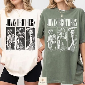 May include: Two short-sleeve crew neck t-shirts, one in ivory and one in moss green. Each shirt features a graphic print with the text JONAS BROTHERS above three vertical panels displaying black and white illustrations of band members.