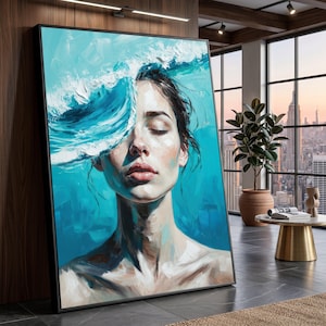 Puede incluir: Una impresión artística enmarcada que presenta a una mujer con los ojos cerrados, parcialmente cubierta por una ola estilizada. La obra de arte utiliza una paleta de azules y blancos, creando una representación serena y artística. La pintura se exhibe en un entorno interior moderno.