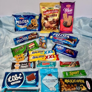 Può includere: Una collezione di vari snack confezionati, tra cui barrette di cioccolato, biscotti e caramelle. I marchi visibili includono Pilóta, Győri Édes, Detki Mese, Boci, Balaton, Tibi, Cerbona, Spiler, Piros Mogyorós, Sport e Mogyi Mexicorn in confezioni colorate.