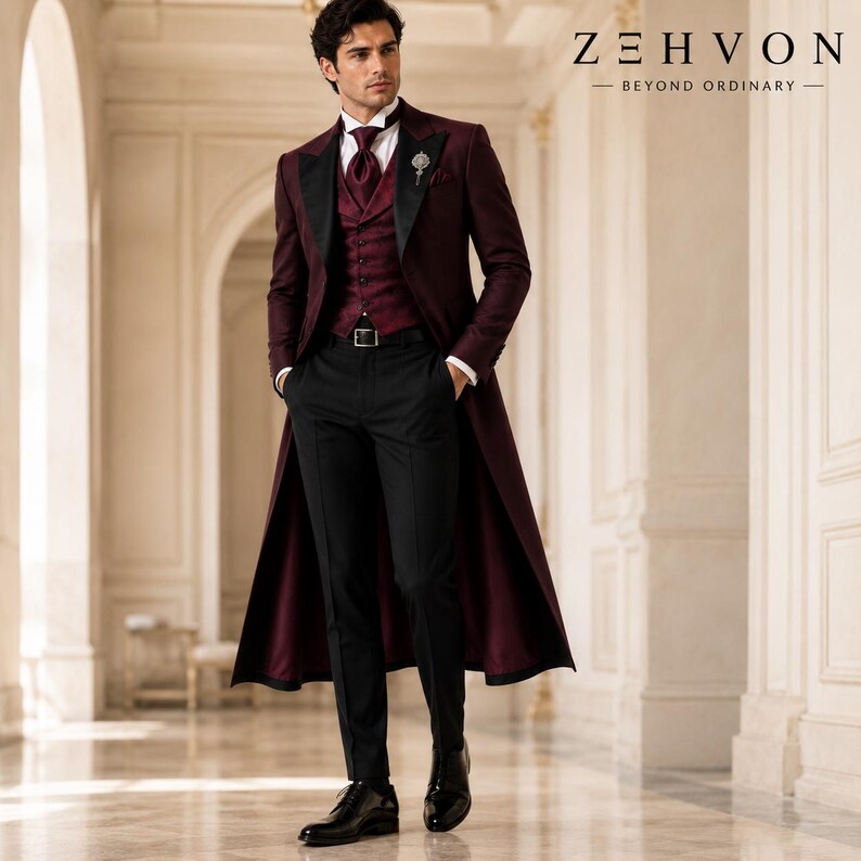 May include: A burgundy long coat with black lapels, a matching burgundy vest, a white dress shirt, a burgundy tie, and black trousers. The outfit includes a silver lapel pin and black dress shoes. The text ZEH VON BEYOND ORDINARY is visible.
