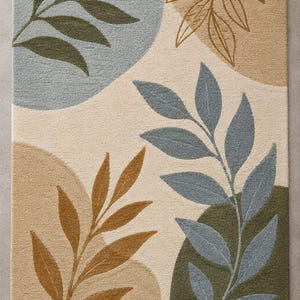 May include: A rectangular area rug featuring a cream-colored background with abstract shapes in muted tones of sage green, dusty blue, and tan. The design includes detailed leaf patterns in dark green, blue, and brown outlines across the surface.