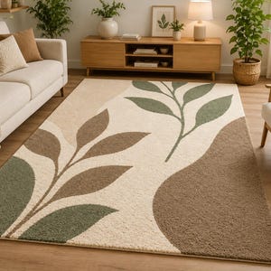 May include: A rectangular area rug featuring a cream-colored background with large, stylized leaf patterns in shades of sage green and earthy brown. The design includes organic, curved shapes and a textured surface that covers the floor space.