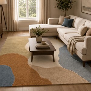 May include: A rectangular area rug featuring an abstract pattern of large, organic shapes in muted tones of cream, beige, burnt orange, and slate blue. The rug has a textured, low-pile surface and covers a significant portion of the wooden floor.