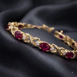 May include: A gold link bracelet featuring alternating oval-cut deep red rubies and small round-cut clear diamonds. The metal links are designed in a repeating X-shaped pattern that connects each gemstone setting along the entire length of the piece.