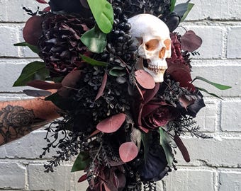 Ramo de novia alternativo con calavera gótica en cascada, flores oscuras y melancólicas.