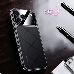 May include: A black smartphone case with a textured diamond-patterned back and a glossy camera module area. The case features a metallic silver frame and the word HAPPY embossed vertically on the lower left side. A pen and paper are nearby.