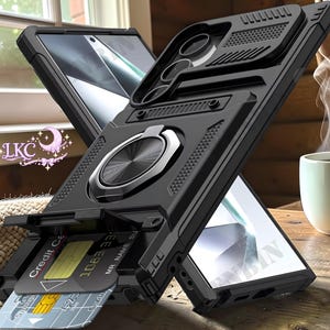 May include: Black phone case with a built-in card holder and a silver ring holder. The case has a rugged design with textured details and a kickstand feature. A credit card is partially visible in the card slot.