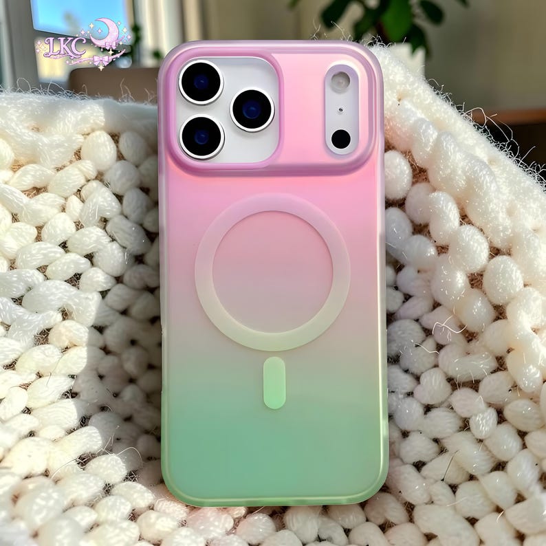 Puede incluir: Una funda para smartphone con un degradado vertical que transiciona de rosa en la parte superior a verde claro en la inferior. La funda incluye un anillo magn&eacute;tico MagSafe circular en el centro y un recorte rectangular para la c&aacute;mara con tres lentes.
