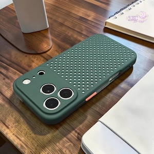 May include: A dark green smartphone case featuring a perforated dot pattern on the back panel and a raised camera module with three circular lens cutouts. A small orange accent button is visible on the side of the protective cover.