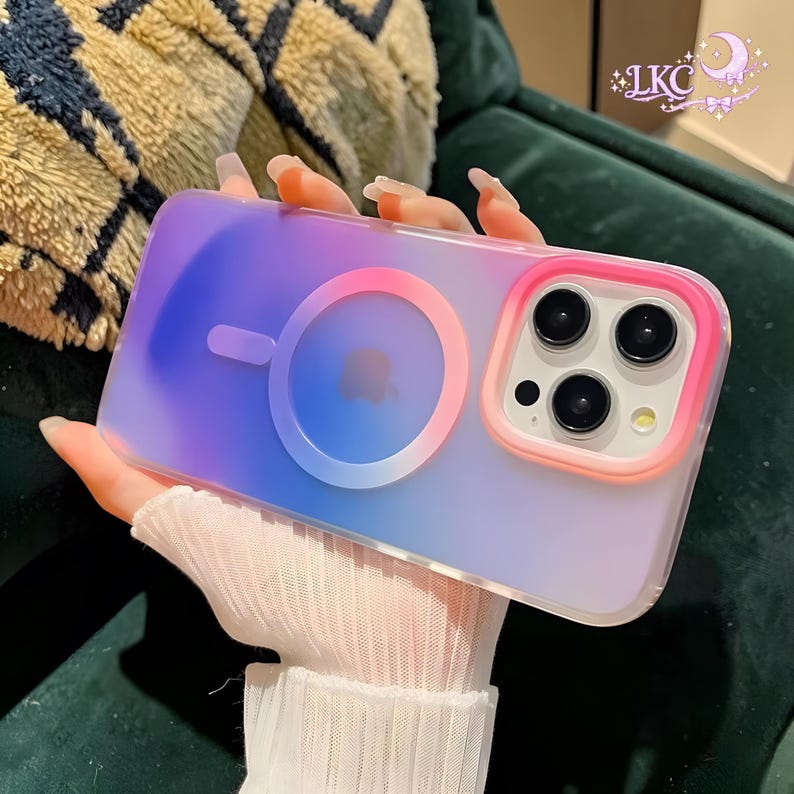 Puede incluir: Una funda para smartphone con un degradado de azul y morado y un anillo de carga magn&eacute;tico circular en el centro. El m&oacute;dulo de la c&aacute;mara est&aacute; rodeado por un marco rosa y naranja. El texto LKC es visible en la esquina superior derecha.