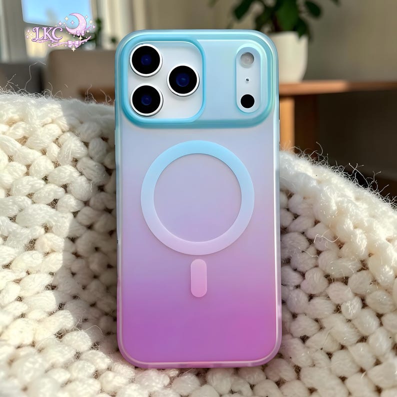 Puede incluir: Una funda para smartphone con un degradado suave que va del azul claro en la parte superior al rosa intenso en la inferior. La funda incluye un anillo de carga magn&eacute;tico circular en el centro y un recorte elevado para tres lentes.