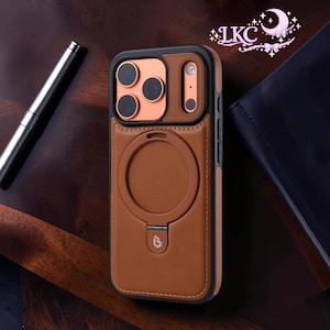 Puede incluir: Funda de teléfono de cuero marrón con borde negro y detalles cobrizos para la cámara. La funda presenta un área de fijación magnética circular y un pequeño logotipo en la parte inferior. La funda está diseñada para proteger el teléfono.