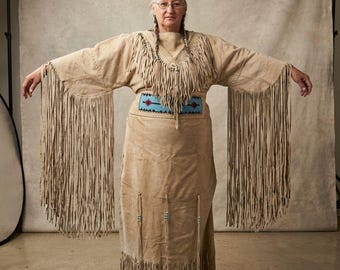 Vestido tradicional nativo americano de piel de venado con flecos, cinturón y mangas adornados con cuentas – Atuendo cultural étnico artesanal de inspiración vintage.
