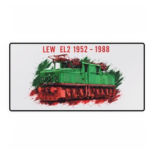 May include: A rectangular desk mat featuring a green and red electric locomotive illustration. The text LEW EL2 1952 - 1988 is printed in red above the train. The design includes a green and red paint splatter effect behind the locomotive.