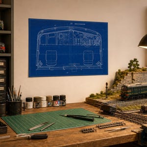 Puede incluir: Una impresión de plano técnico azul que presenta un dibujo lineal detallado del interior de la cabina de una locomotora, exhibido en una pared sobre un banco de trabajo equipado con suministros, herramientas y una vía de tren en miniatura.