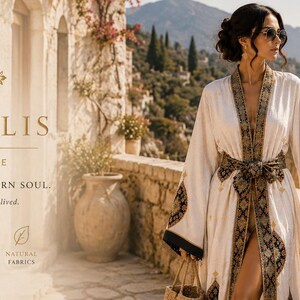 Peut inclure: Une robe blanche avec une bordure à motifs foncés le long de l'ouverture avant, de la ceinture et des manches larges. Le texte ANATOLIS LUMA HOME HERITAGE WOVEN. MODERN SOUL. Timeless textiles for a life well lived. est visible à gauche.