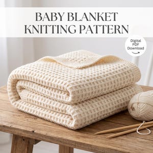 May include: A folded cream-colored baby blanket with a waffle knit texture. The text BABY BLANKET KNITTING PATTERN and Digital PDF Download are visible. A ball of matching yarn and two wooden knitting needles are placed next to the blanket.