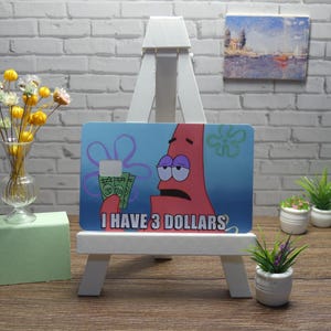 Vinilo adhesivo impermeable para tarjeta de crédito con diseño de Patrick Star y la frase "Tengo 3 dólares".