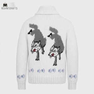 May include: A white knit sweater featuring a shawl collar and long sleeves. The back displays two grey wolf illustrations with red accents, positioned above a row of light blue paw prints. Additional light blue paw prints decorate each sleeve cuff.