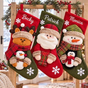 May include: Three personalised Christmas stockings featuring embroidered names Becky, Patrick, and Monica. The stockings display plush appliqués of a reindeer, Santa Claus, and a snowman, each wearing winter accessories and holding small holiday figures.