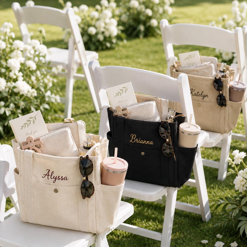 May include: Three canvas tote bags in cream and black, each personalized with embroidered names Alyssa, Brianna, and Katelyn. The bags feature multiple exterior pockets, containing a tumbler, sunglasses, a small pouch, and a thank you card.