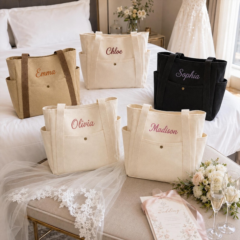 May include: Five canvas tote bags in beige, cream, and black, each featuring two side pockets, a front pocket with a snap button, and two shoulder straps. The bags are embroidered with the names Emma, Chloe, Sophia, Olivia, and Madison in script.