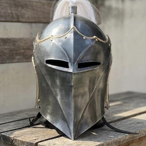 Middeleeuwse ridderhelm met messing afwerking, stalen harnas met pluim en open vizier, voorhoede met vleugels.