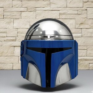 May include: A full-face helmet featuring a polished silver metallic dome and a deep blue faceplate. The design includes a horizontal black visor opening, silver cheek plates, and a distinct T-shaped visor section with a smooth, glossy finish.