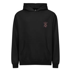 Peut inclure: Un sweat à capuche noir avec une poche avant et une capuche. Un petit motif stylisé, brun rougeâtre, est sur le haut de la poitrine gauche. Le sweat à capuche est en matière souple.