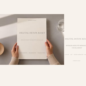 Könnte beinhalten: Ein cremefarbenes Buch mit dem Titel "DIGITAL DETOX RESET" wird von zwei Händen gehalten. Der Text "WENIGER REIZE FÜR MEHR RUHE IM ALLTAG" steht unter dem Titel. Eine Holzschale und ein Glas Wasser sind sichtbar.