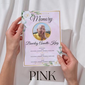 May include: A pink memorial card held by hands, with a photo of a person in a yellow shirt. The card has floral accents, gold borders, and the text "In Loving Memory" and "PINK".