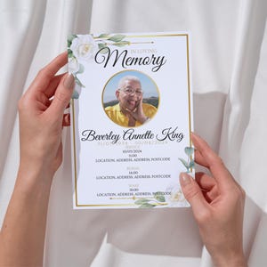 May include: A memorial card held by two hands, featuring a portrait within a gold-bordered circle. The card reads "In Loving Memory" above the name "Beverley Annette King" and dates. Floral and greenery accents frame the text.