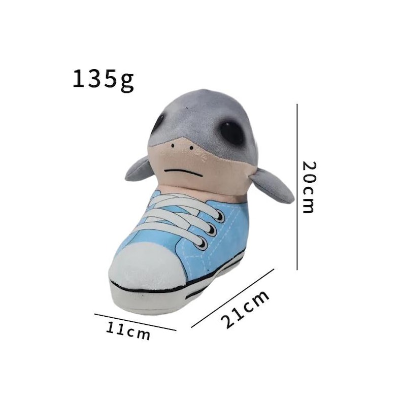 K&ouml;nnte beinhalten: Ein Pl&uuml;schtier in Form eines hellblauen Sneakers mit wei&szlig;en Schn&uuml;rsenkeln und einer wei&szlig;en Zehenkappe. Ein grauer Robbenkopf ragt aus der Oberseite heraus. Das Spielzeug ist 21 cm lang, 11 cm breit und 20 cm hoch und wiegt 135 Gramm.