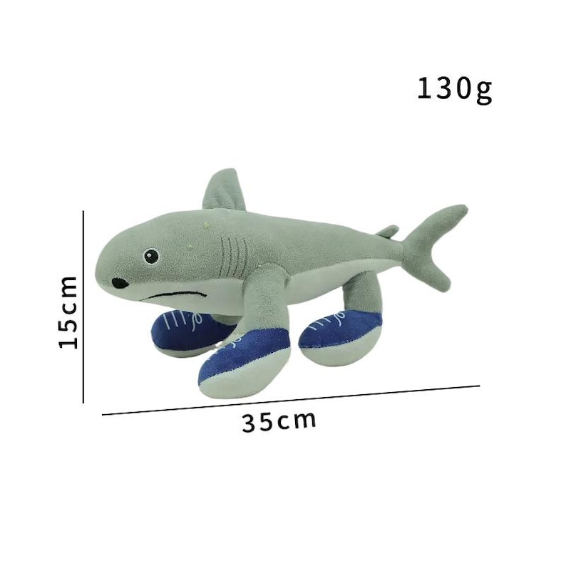 K&ouml;nnte beinhalten: Ein graues Pl&uuml;schhai-Spielzeug, 15 cm hoch und 35 cm lang, mit blauen und wei&szlig;en Turnschuhen. Das Spielzeug wiegt 130g. Der Hai hat eine R&uuml;ckenflosse und eine Schwanzflosse. Das Spielzeug ist f&uuml;r Kinder.