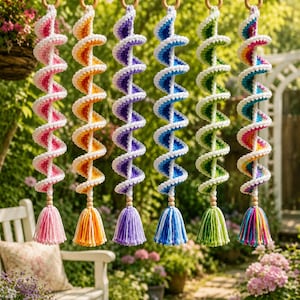 Può includere: Sei decorazioni a spirale sospese realizzate in filato all'uncinetto nei colori rosa, arancione, viola, blu, verde e arcobaleno. Ogni spirale presenta una perlina di legno sul fondo, rifinita con una nappa in filato abbinata appesa a un anello di legno.