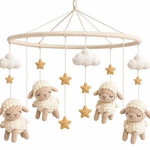 Op de afbeelding: Een hangende mobiel met vier gehaakte schapen met gesloten ogen, drie witte gehaakte wolken en verschillende gele gehaakte sterren, opgehangen aan een cirkelvormig frame omwikkeld met crèmekleurig garen met een centrale ophanglus.