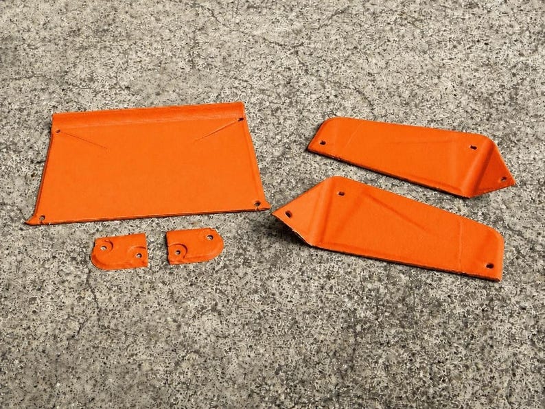 May include: A set of five orange metal components including one large rectangular panel, two elongated trapezoidal pieces, and two small square-shaped brackets, each featuring pre-drilled circular holes for assembly and mounting purposes.
