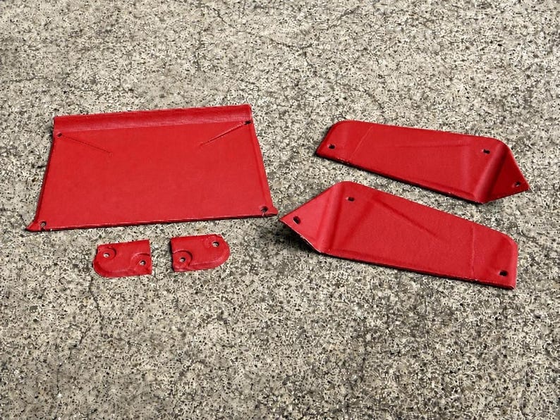 May include: A set of five red metal components featuring a textured finish. The collection includes one large rectangular panel, two elongated angled side pieces, and two small square-shaped brackets, all with pre-drilled holes for mounting.