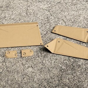 May include: A set of five tan-colored metal components featuring a flat rectangular piece, two elongated trapezoidal panels, and two small square-shaped brackets. Each piece includes pre-drilled circular holes for assembly and mounting purposes.