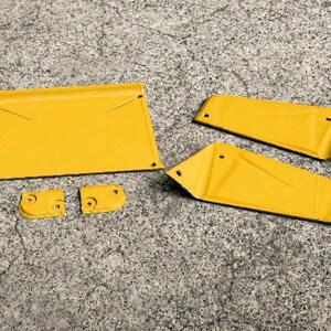 May include: A set of five yellow metal components featuring a large trapezoidal plate, two elongated angled side panels, and two small rectangular brackets, all with pre-drilled holes for assembly and a smooth, uniform painted finish.