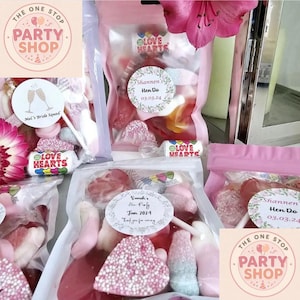 May include: A selection of clear bags filled with pink and white sweets, including heart-shaped candies. The bags are labelled with "Love Hearts" and "The One Stop Party Shop". Some bags have custom labels for events.