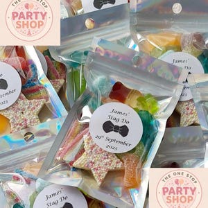 May include: Several cellophane bags filled with a variety of sweets, including star-shaped biscuits and gummy sweets. Each bag features a sticker saying "James' Stag Do" and the date "29th September 2023". The bags are from "The One Stop Party Shop".