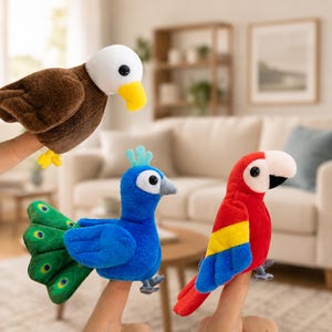 May include: Three plush finger puppets shaped like birds. One is a brown and white bald eagle with a yellow beak, one is a blue peacock with a green tail featuring eye-like patterns, and one is a red, yellow, and blue parrot with a white beak.